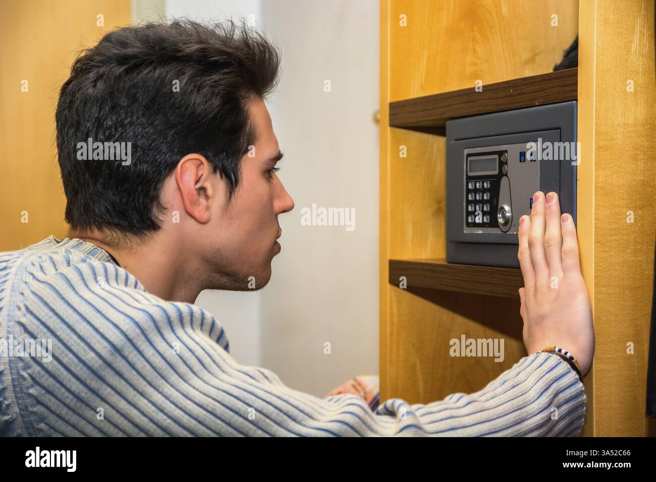 Young handsome man using a small vault or safe in his home Stock Photo