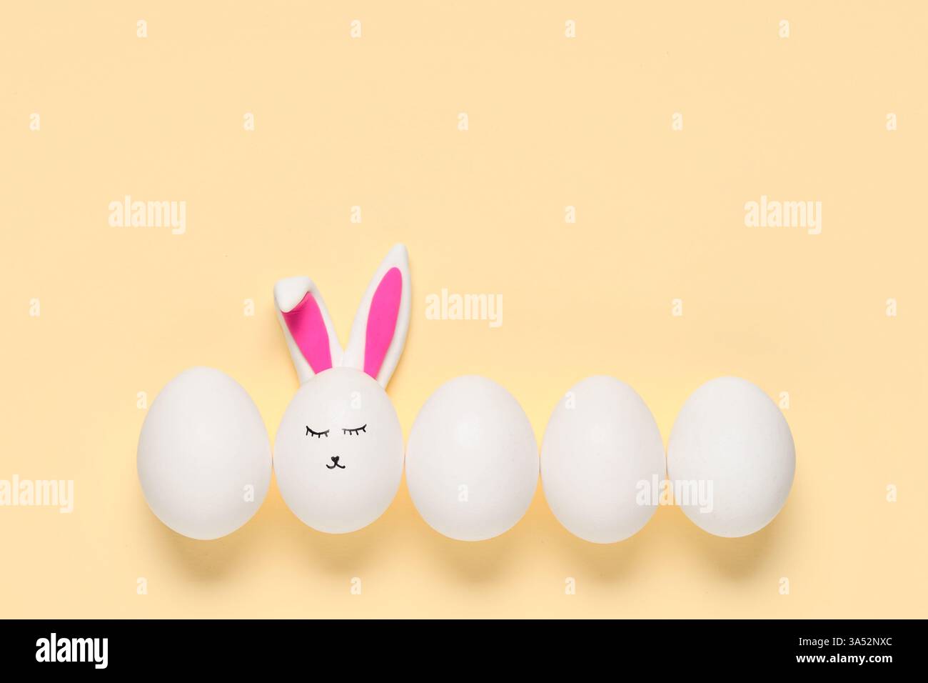 Easter eggs with drawn face and bunny ears on beige background Stock Photo