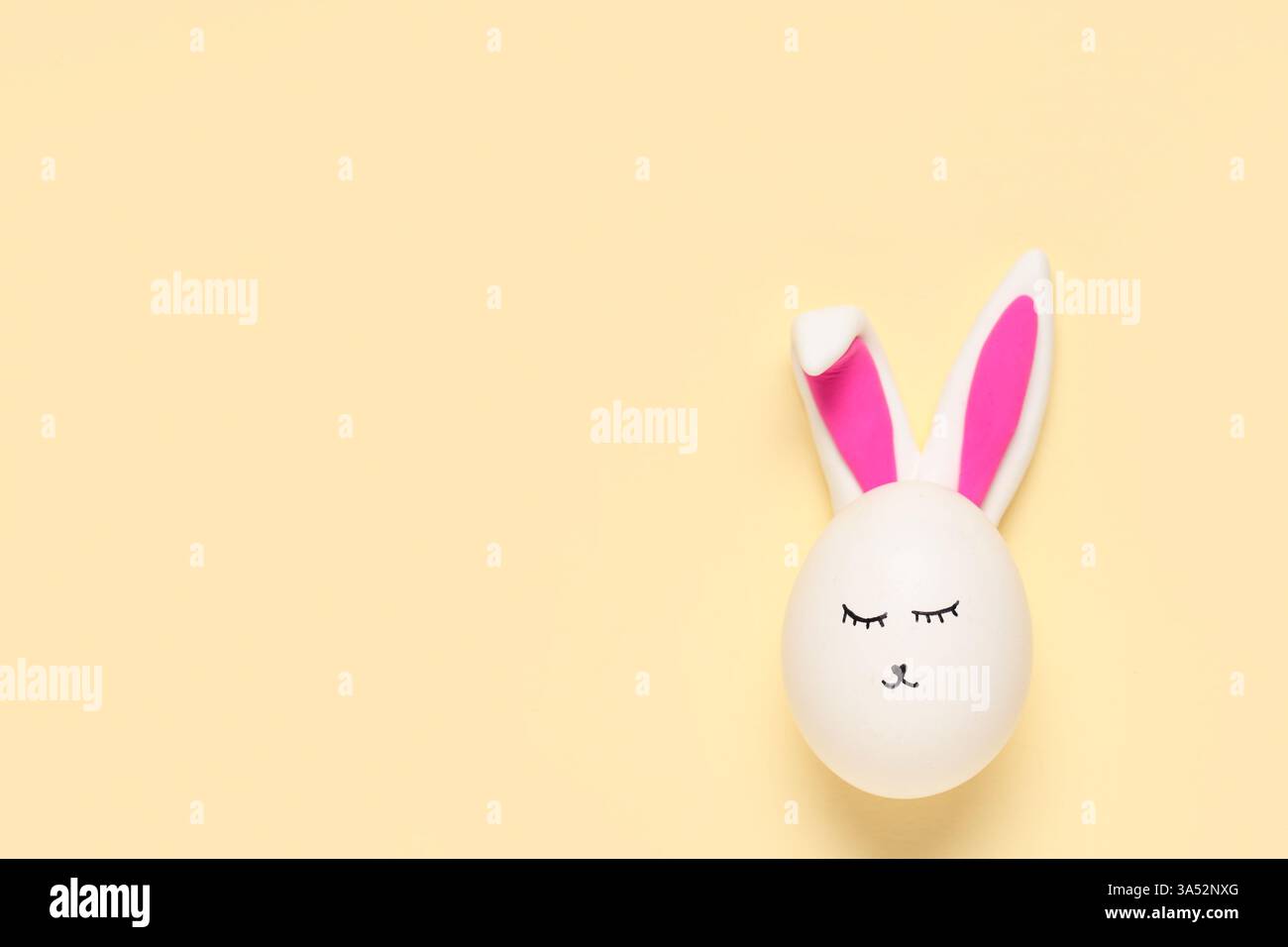 Easter eggs with drawn face and bunny ears on beige background Stock Photo