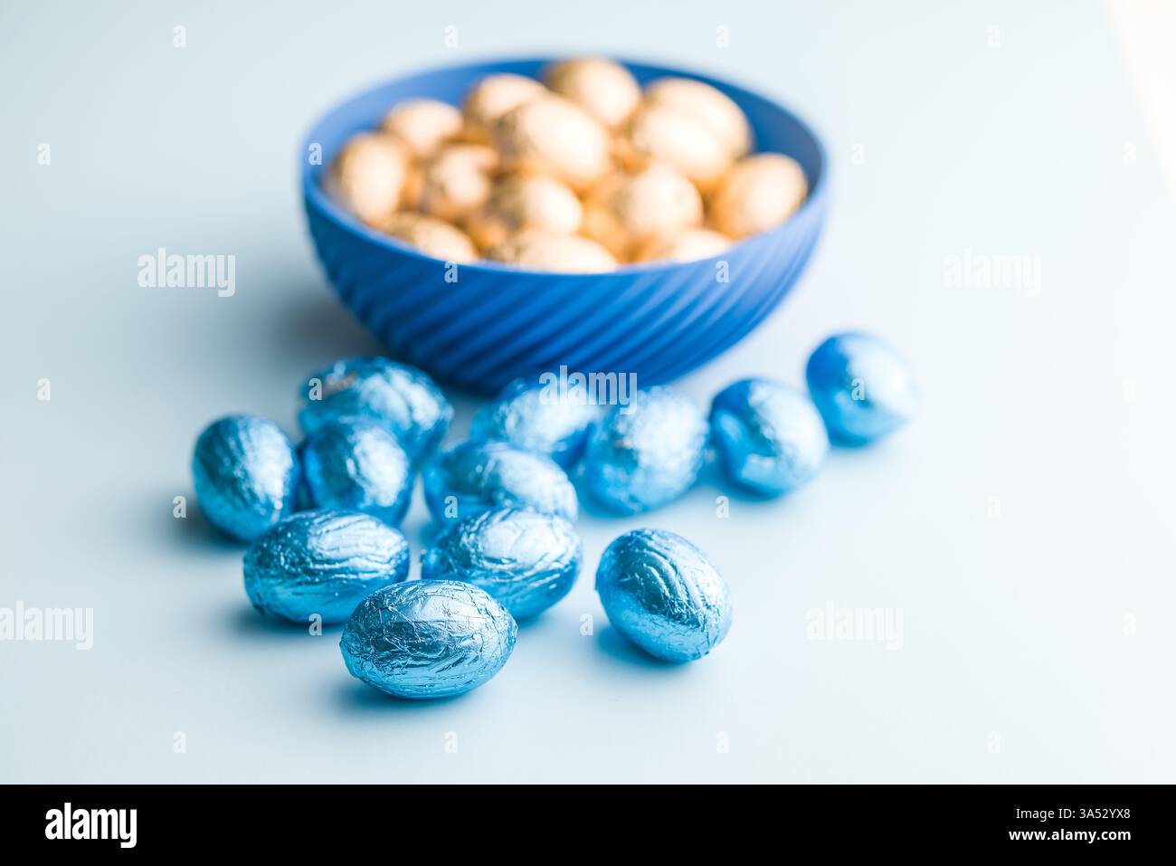 Chocolate easter eggs wrapped in blue colored foil on a blue background. Stock Photo