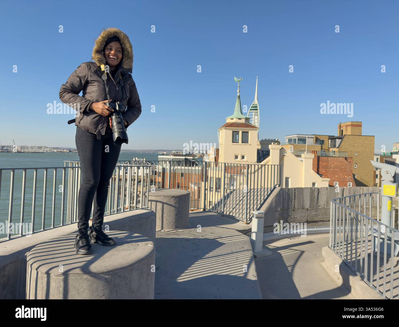 Portsmouth England UK. 18.03.2025. Woman with fur lined hood taking pictures during winter Portsmouth Harbour, Stock Photo