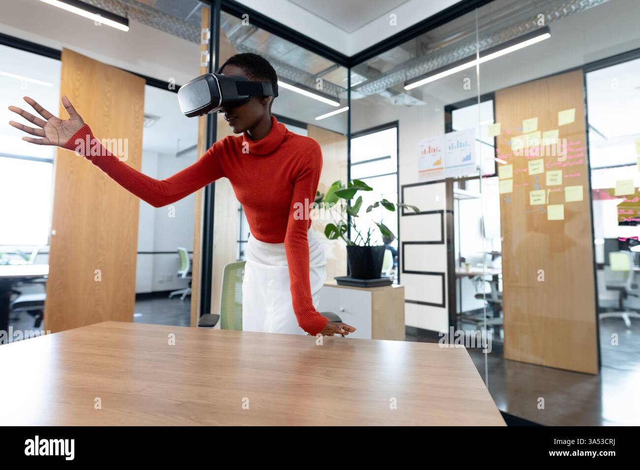 Woman using VR headset in modern office, interacting with virtual environment Stock Photo