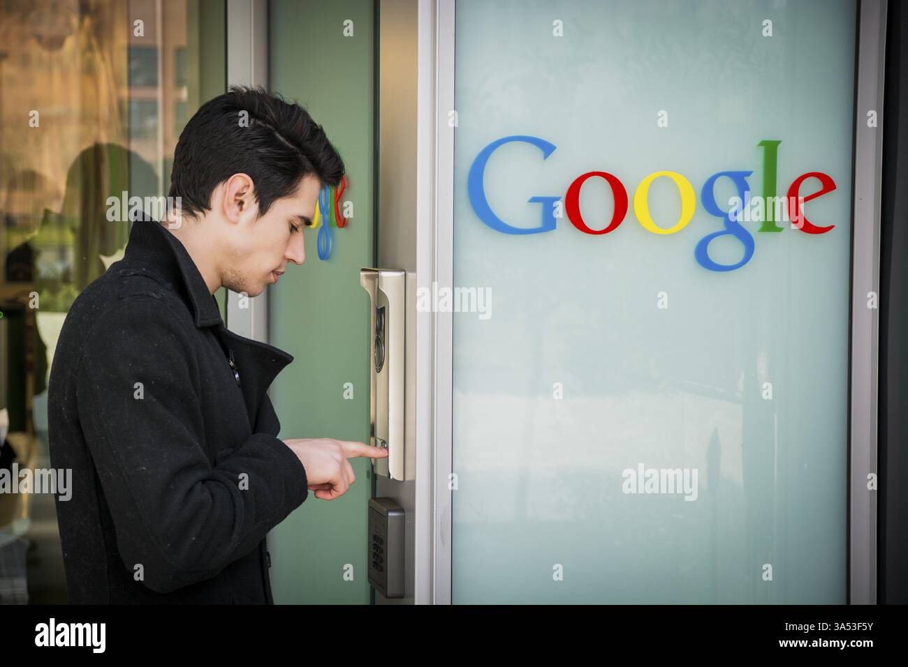 Handsome young man standing ringing the intercom at Google offices Stock Photo