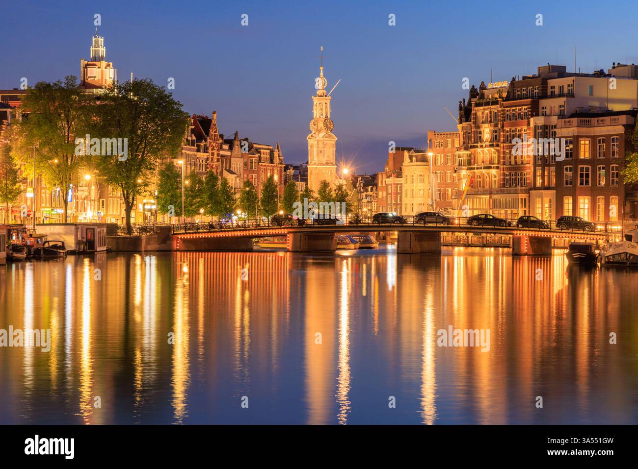 Amsterdam by night in Holland with bright city lights with its canals and old waterfront houses and bridges - a travel image Stock Photo