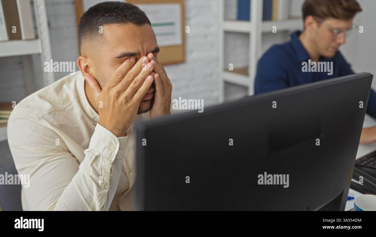 Frustrated man covering his face with hands while working on a computer ...