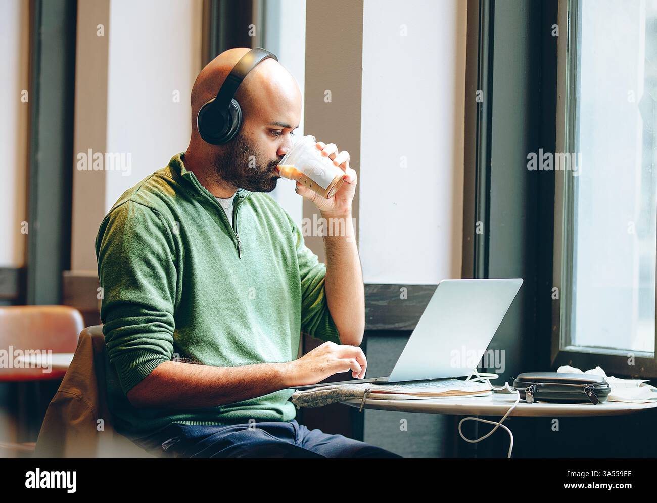 A man using a laptop by the window Stock Photo
