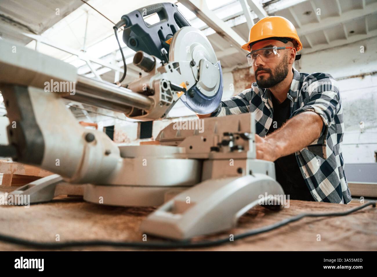 Focused, woodworking. Man is in warehouse. Stock Photo