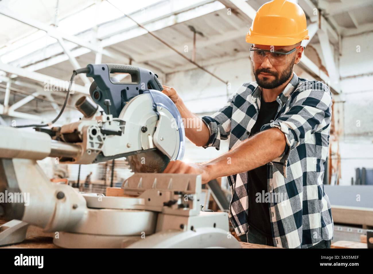 Focused, woodworking. Man is in warehouse. Stock Photo