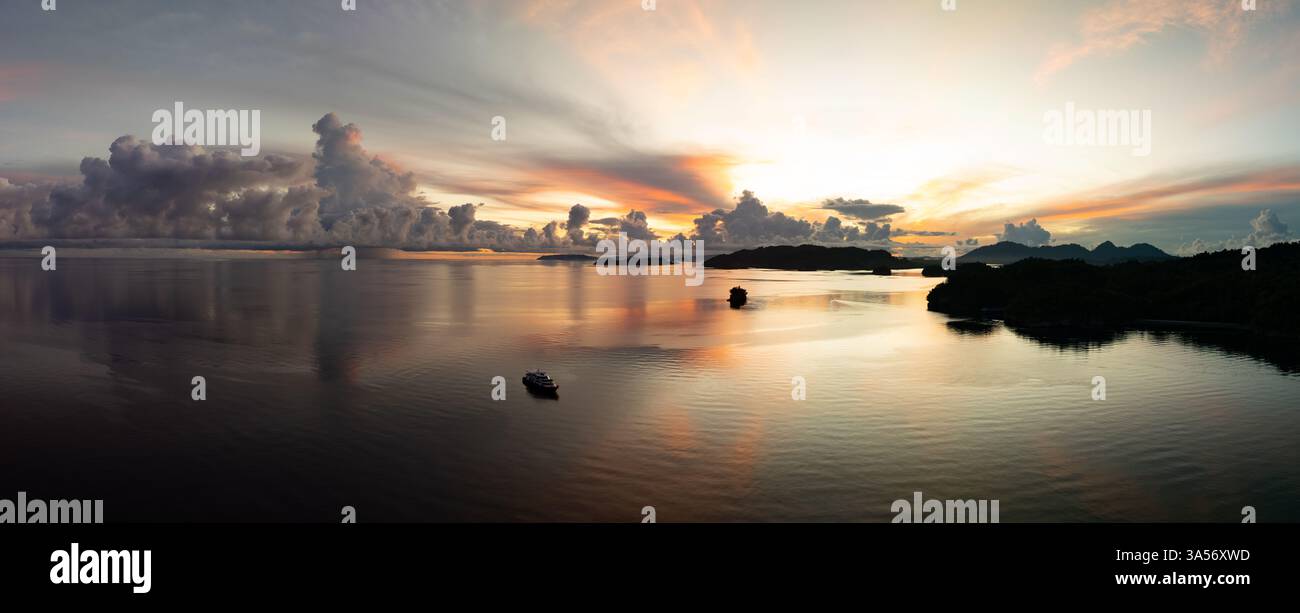 A sunrise illuminates the calm seas surrounding the Togian Island of ...