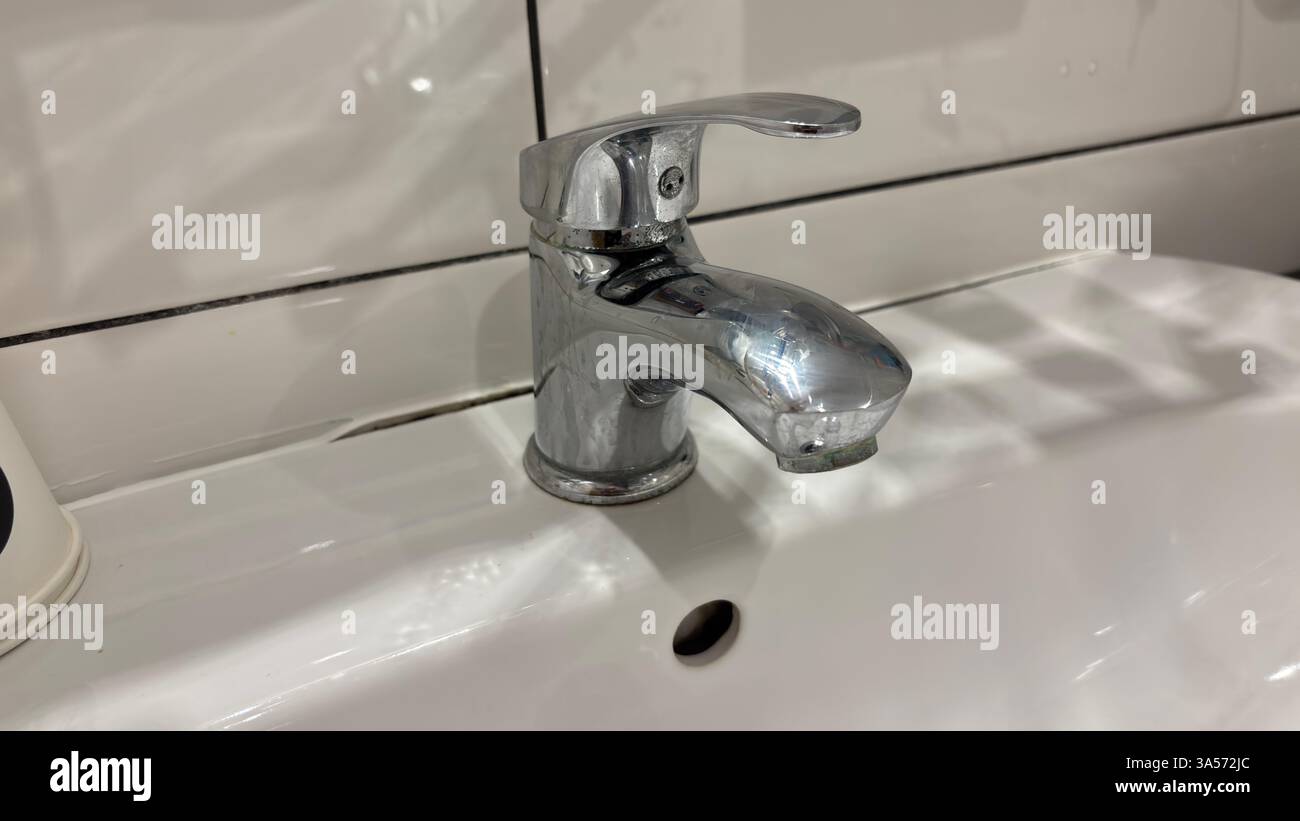 Chrome mixer tap attached to a sink close up. Grubby, dirty decay. Bathroom fittings - Smartphone Captured Stock Image