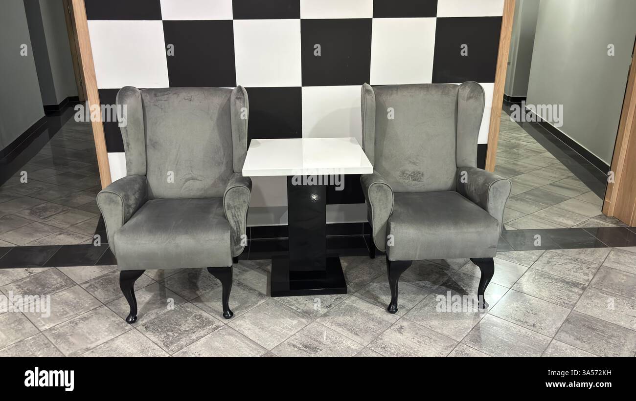 Chairs and table in a hotel lobby. Stylish interior of a hotel. Tiled corridor in a residential apartment. Sterile blank walls. Modern style - Smartphone Captured Stock Image