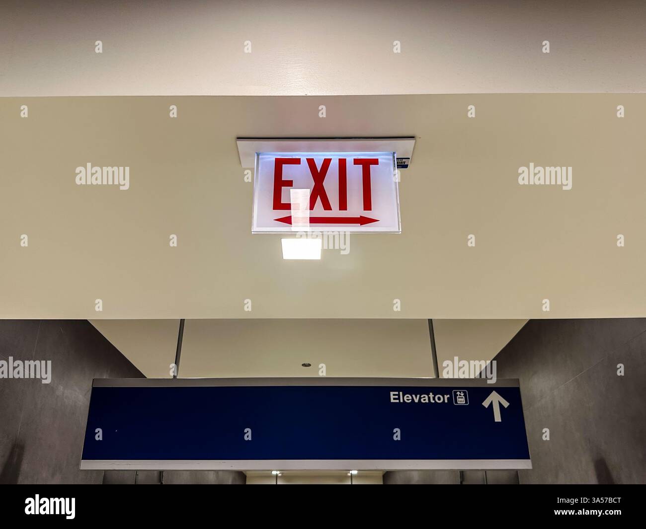 Exit sign above an elevator sign inside a building - Smartphone Captured Stock Image