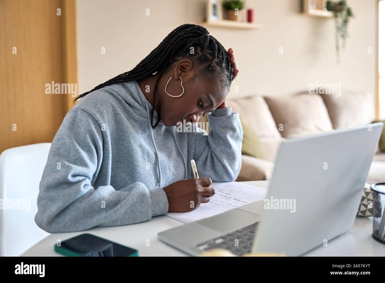Focused black woman taking notes while studying at home Stock Photo