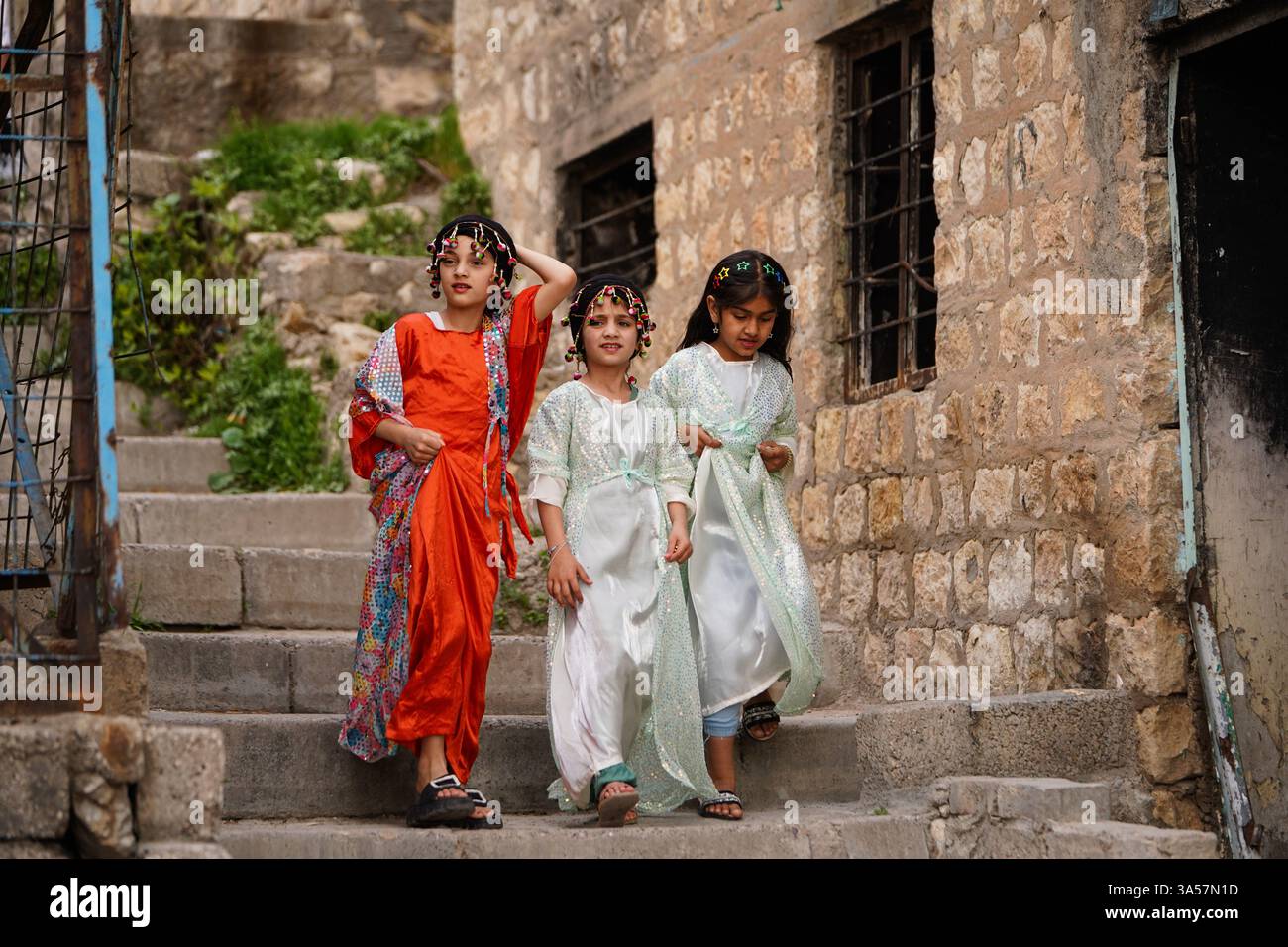 Iraqi Kurdish children wearing traditional clothes walk in an old alley ...