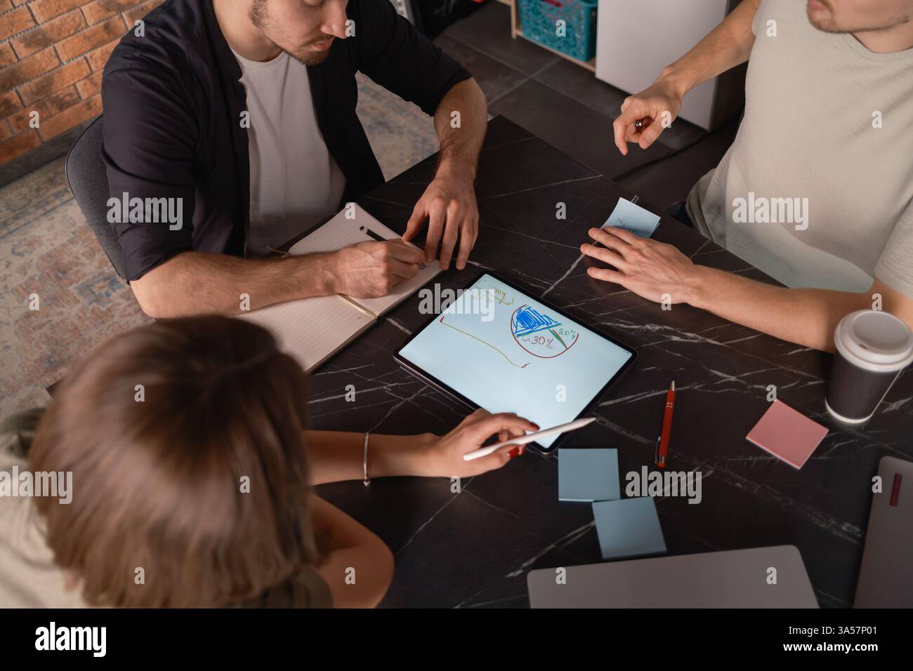 Team collaboration using a tablet in a modern workspace setting. Stock Photo