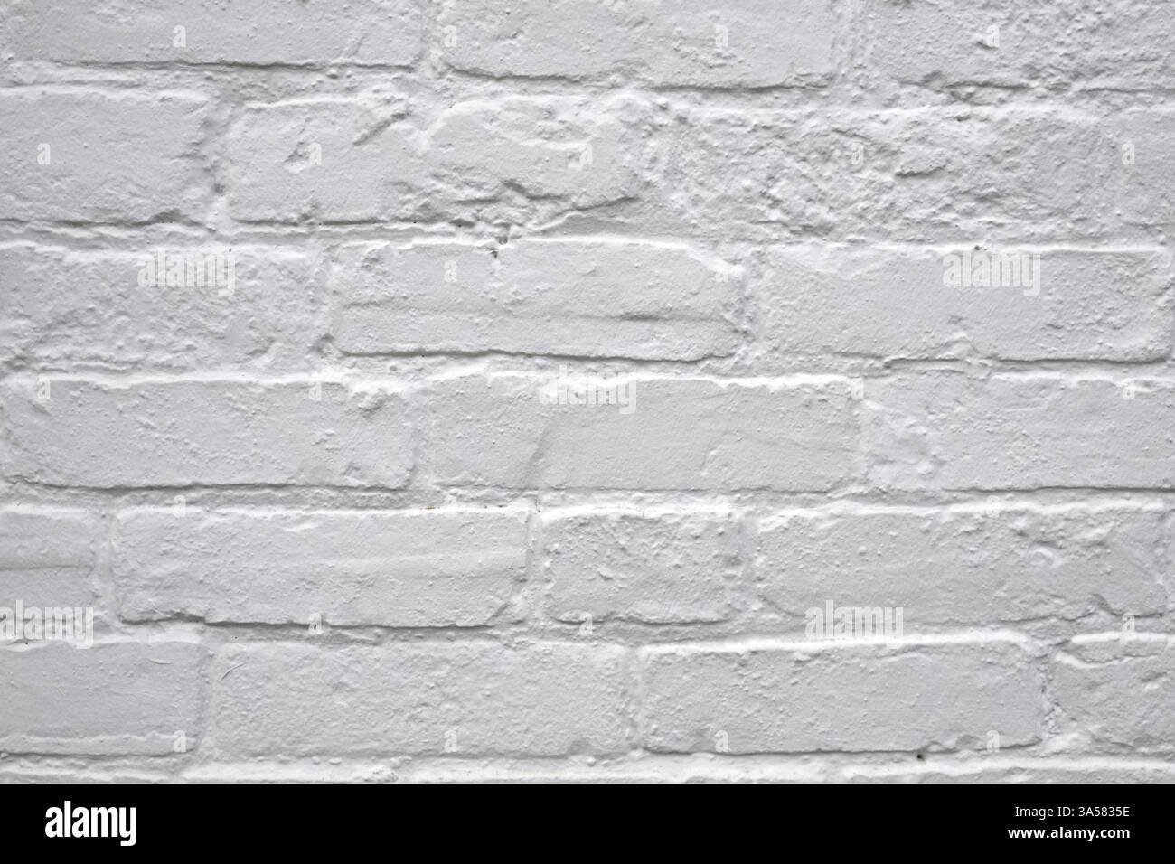 A white brick wall with a few bricks missing. The wall is very plain and simple Stock Photo
