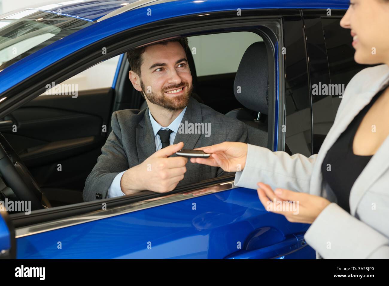 Happy saleswoman giving key to client inside new car in salon Stock ...