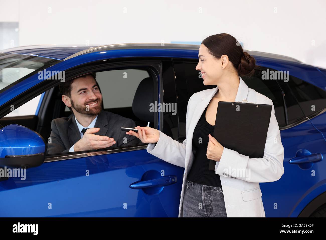 Happy saleswoman giving key to client inside new car in salon Stock ...