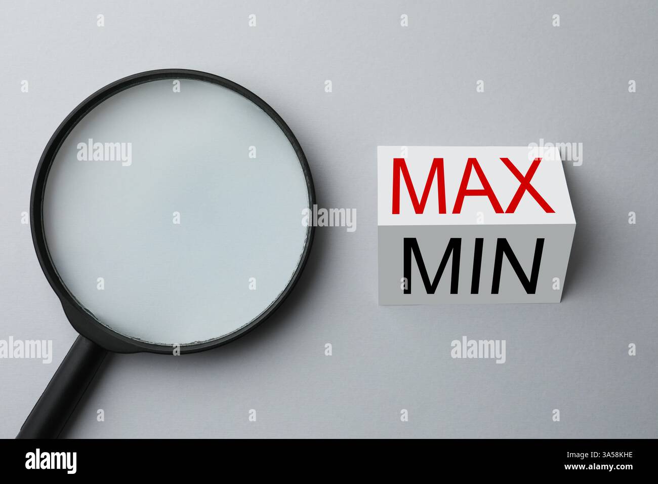 Magnifying glass near sheet of paper with words Max and Min on light ...