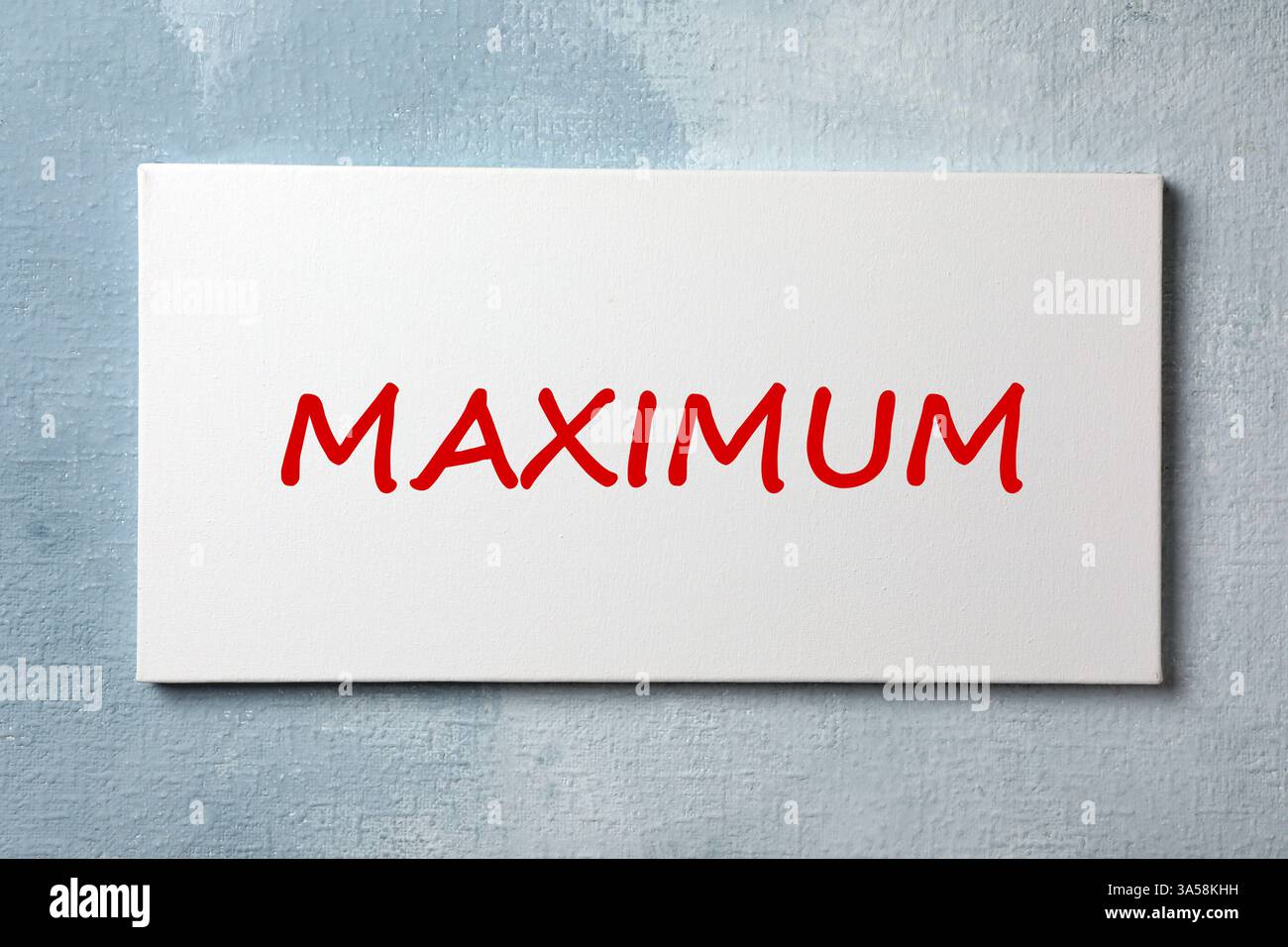 Canvas with word Maximum on light blue textured background Stock Photo
