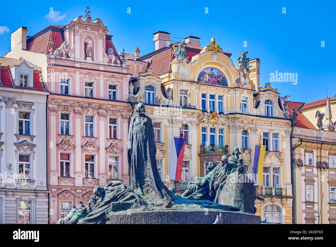 The Jan Hus Memorial is over 100 years old stands at one end of Old Town Square with row of coloured houses in background, Prague, Czech Republic Stock Photo