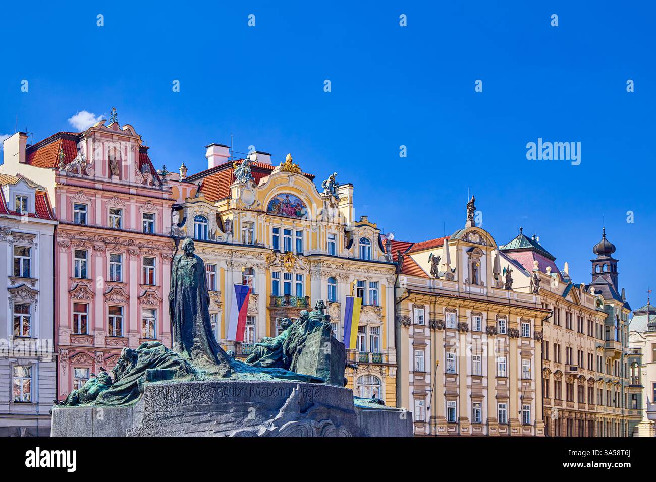 The Jan Hus Memorial is over 100 years old stands at one end of Old Town Square with row of coloured houses in background, Prague, Czech Republic Stock Photo