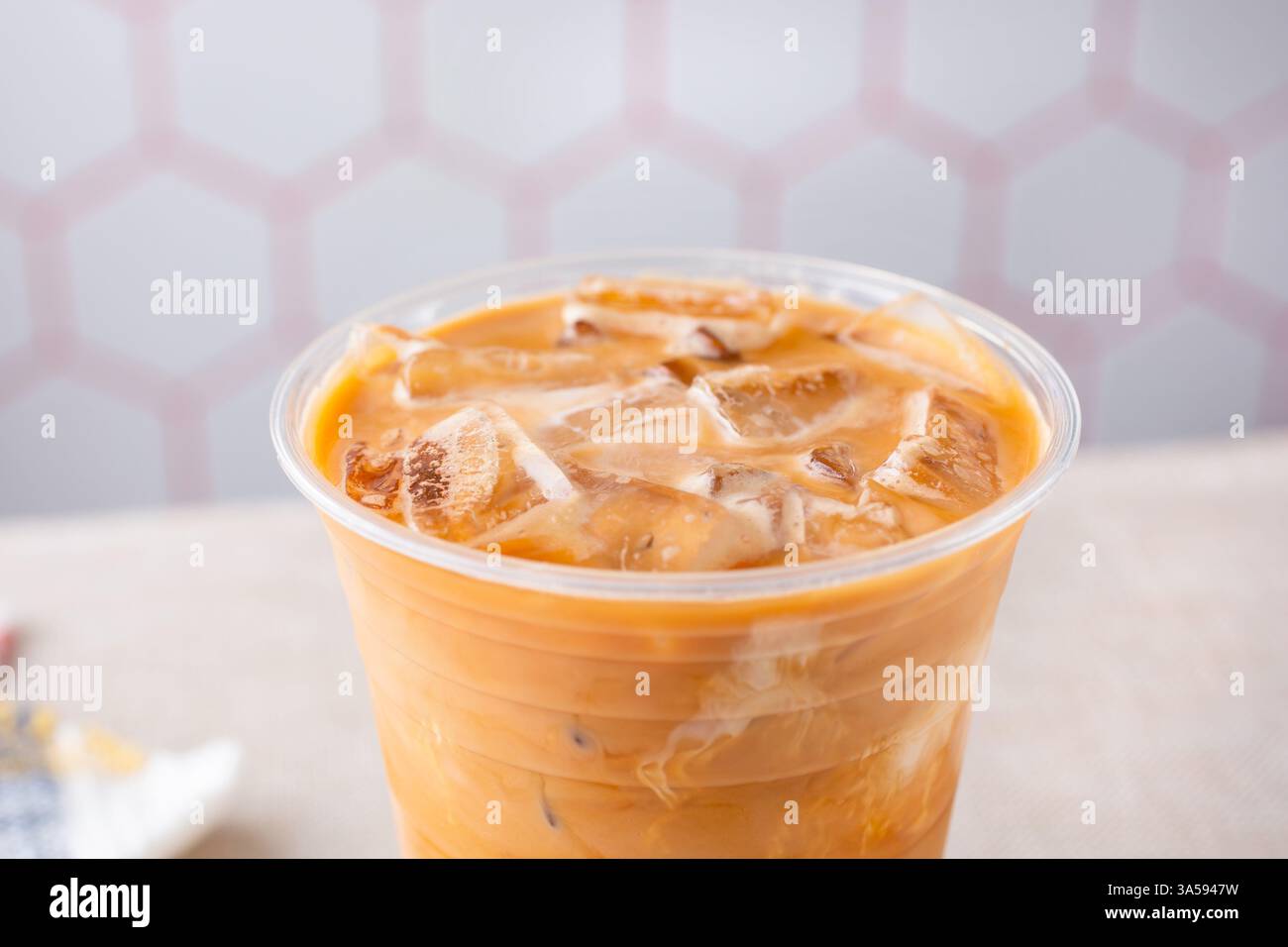A closeup view of a Thai iced tea in a clear plastic cup. Stock Photo