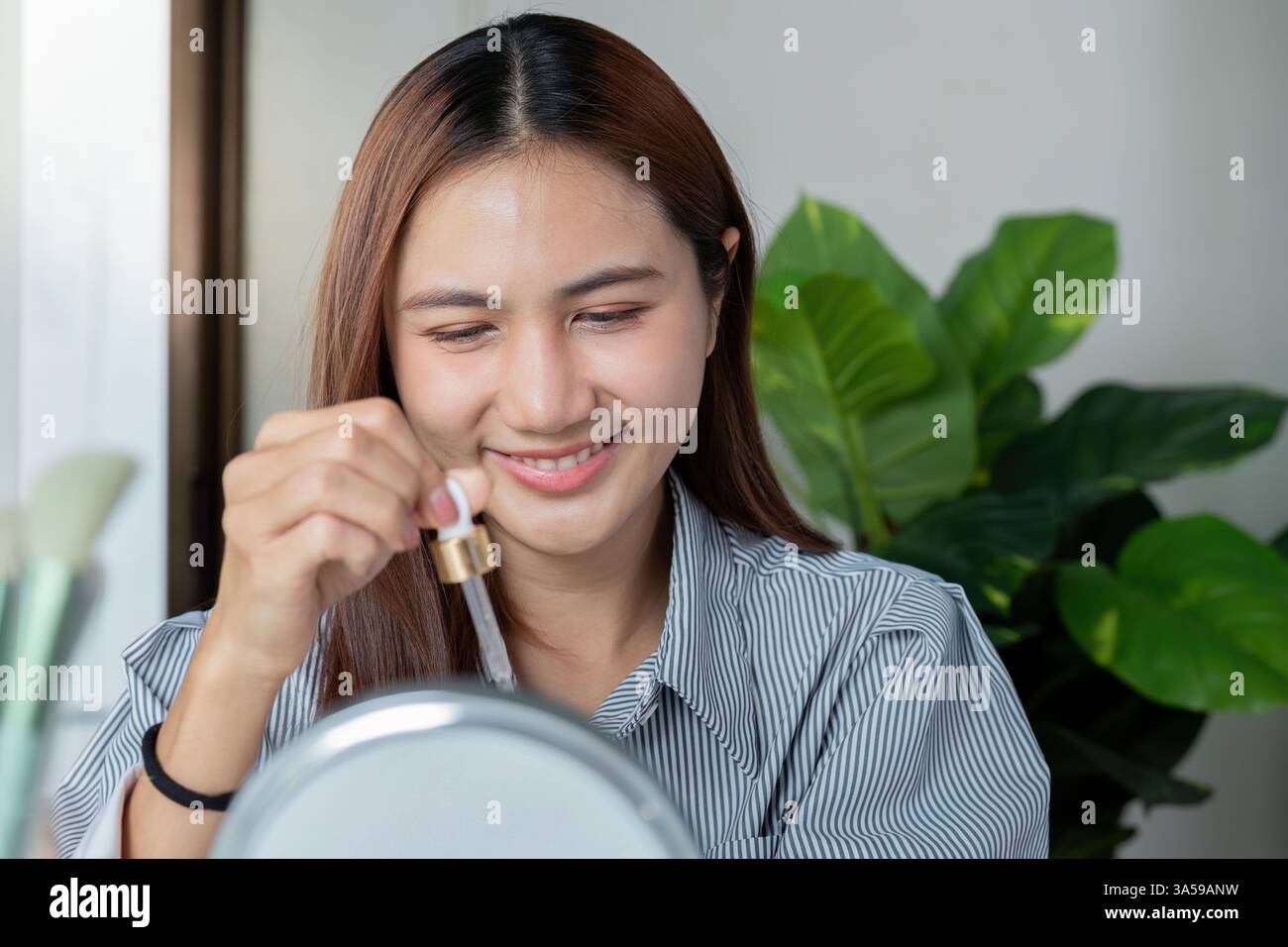 Joy and Skincare Routine. A woman applies serum while smiling ...