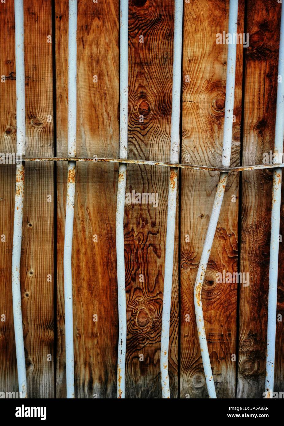 A close-up view of a rustic wooden wall features vertical white metal bars that add texture and contrast. - Smartphone Captured Stock Image