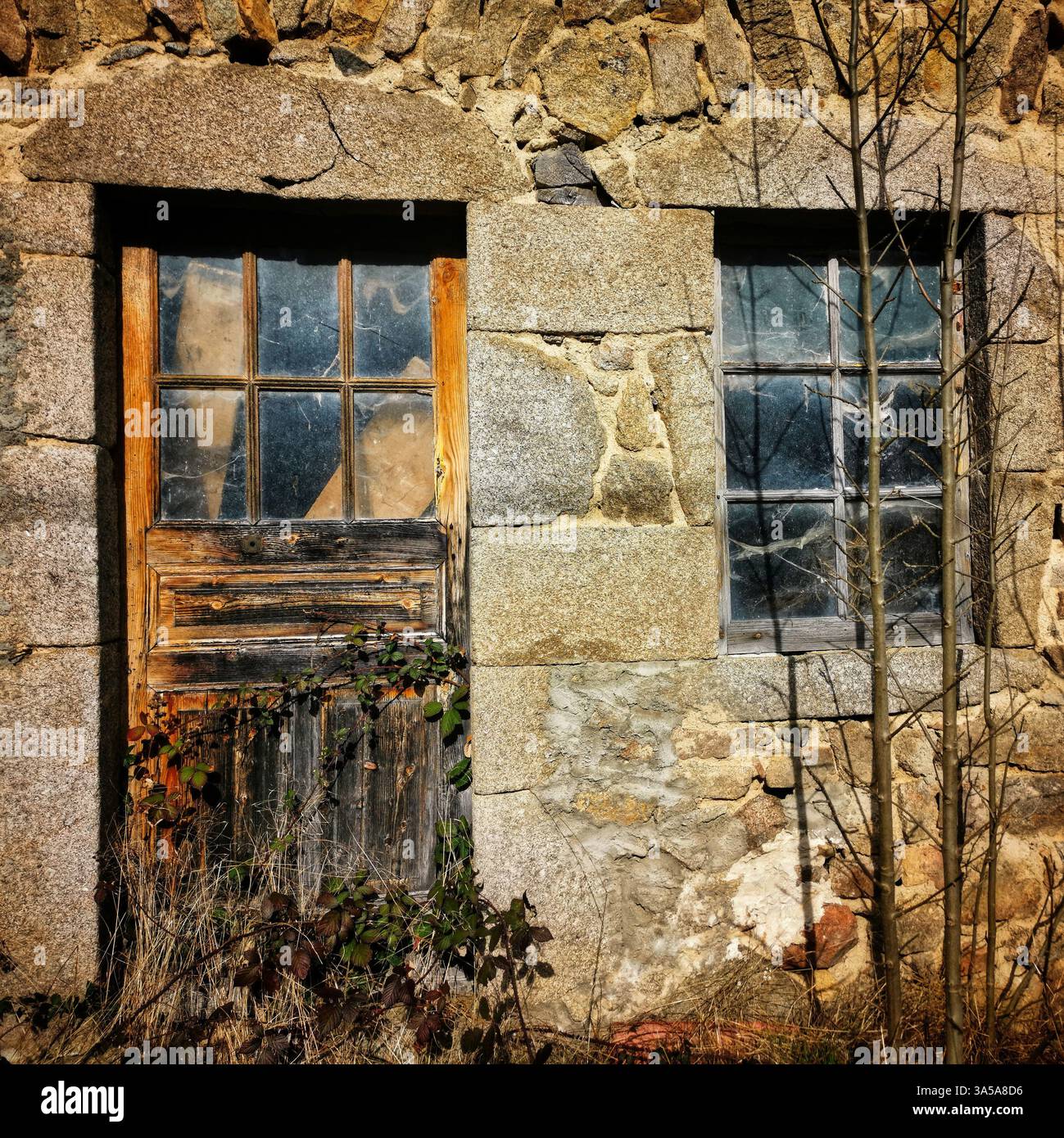 Rustic stone building abandoned with weathered doors and windows in a sunlit landscape. Auvergne. France - Smartphone Captured Stock Image