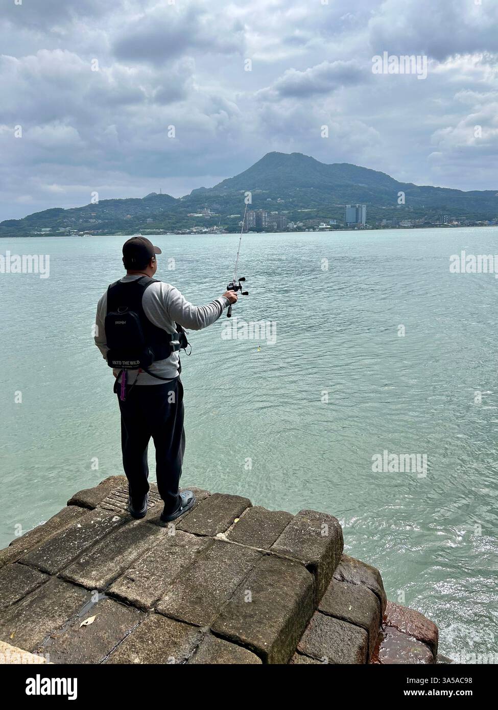New Taipei, Taiwan, Scenic View, Local Fisherman Fishing From Behind, on Tamsui River, Landscape View of Guanyin Mountain - Smartphone Captured Stock Image