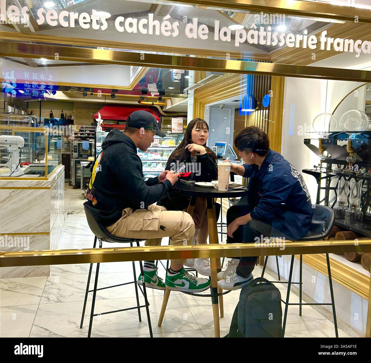 Taipei, Taiwan, Group Taiwanese Teenagers sitting at Local French Cafe Table on Terrace Talking, at Night - Smartphone Captured Stock Image