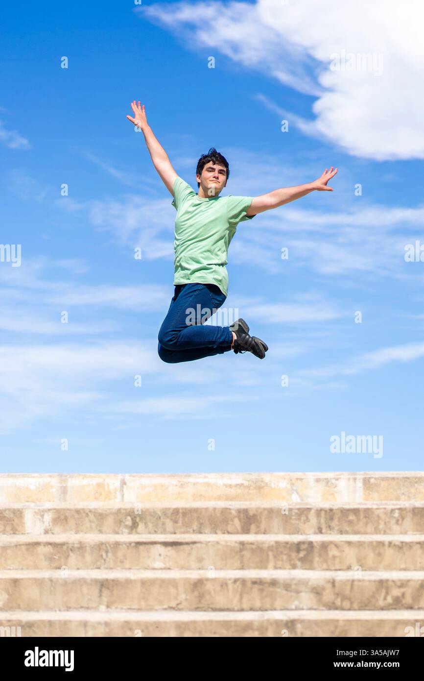 Energetic young man jumping with joy against a clear blue sky Stock Photo