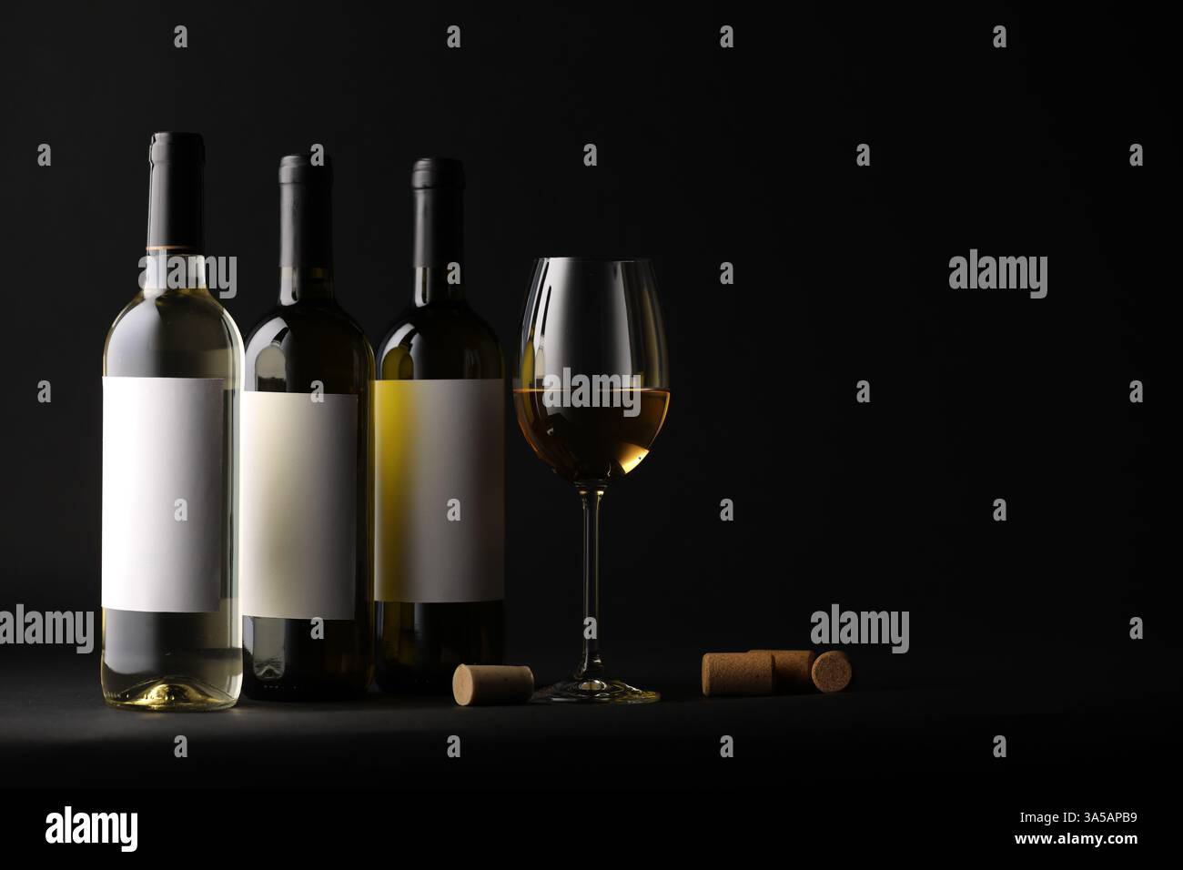 Tasty wine in glass, bottles and corks on black background, space for text Stock Photo