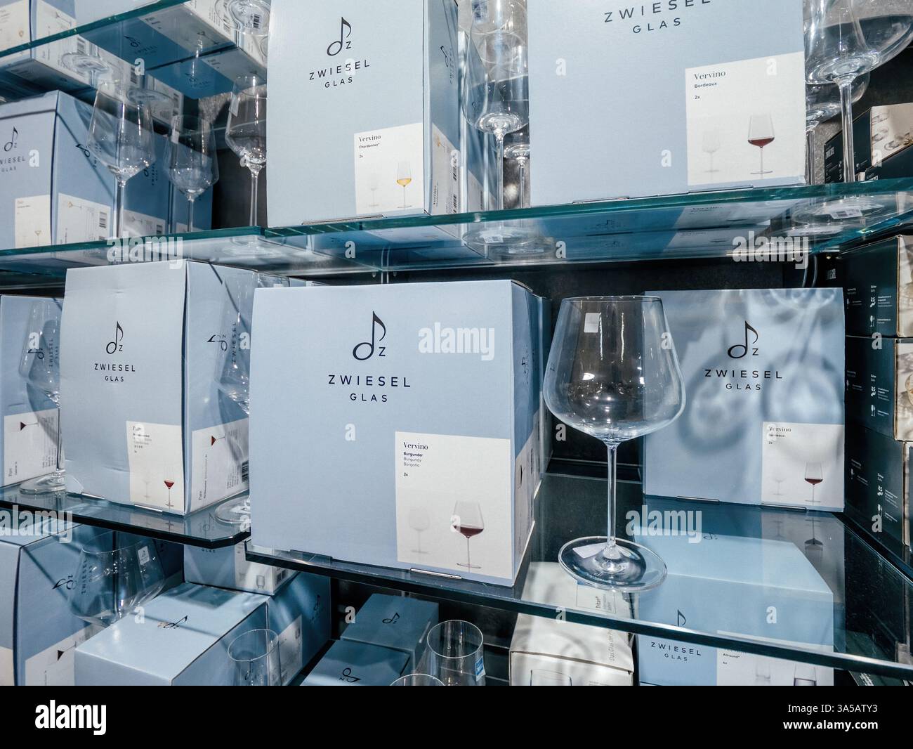 Freiburg, Germany - Feb 10, 2025: Shelves are stacked with Zwiesel Glas boxed glassware and displayed wine glasses in a refined retail setting with so Stock Photo