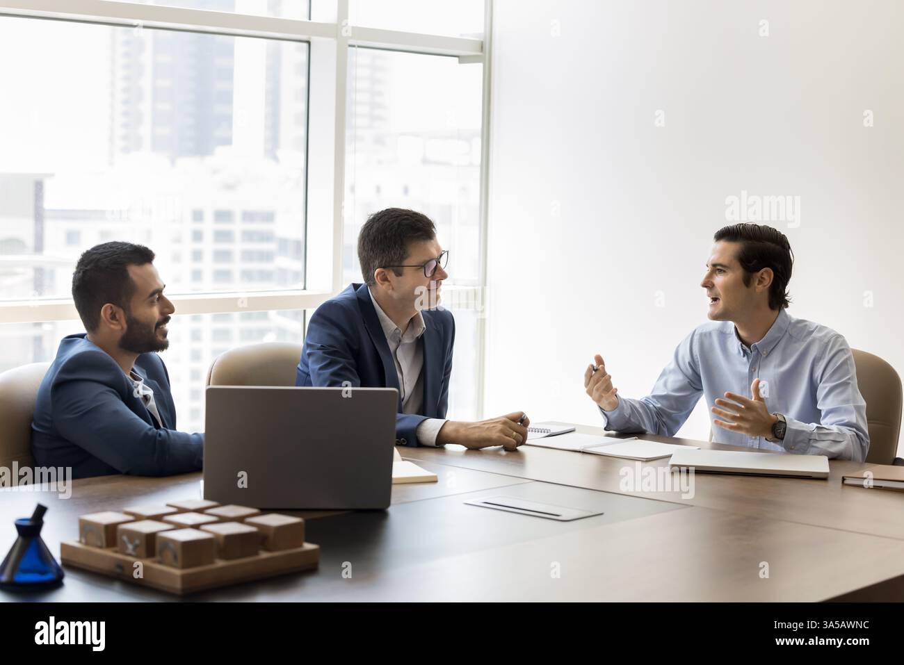 Three professionals engaged in discussion seated at conference table Stock Photo