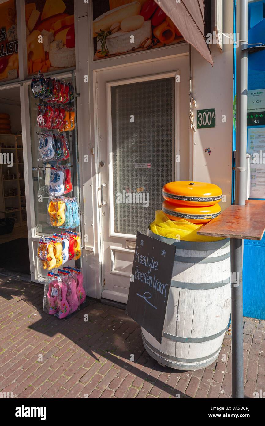 Traditional Dutch cheese on a barrel and colourful wooden clogs at a souvenir shop in fishing village and tourist resort Scheveningen, The Netherlands. Stock Photo