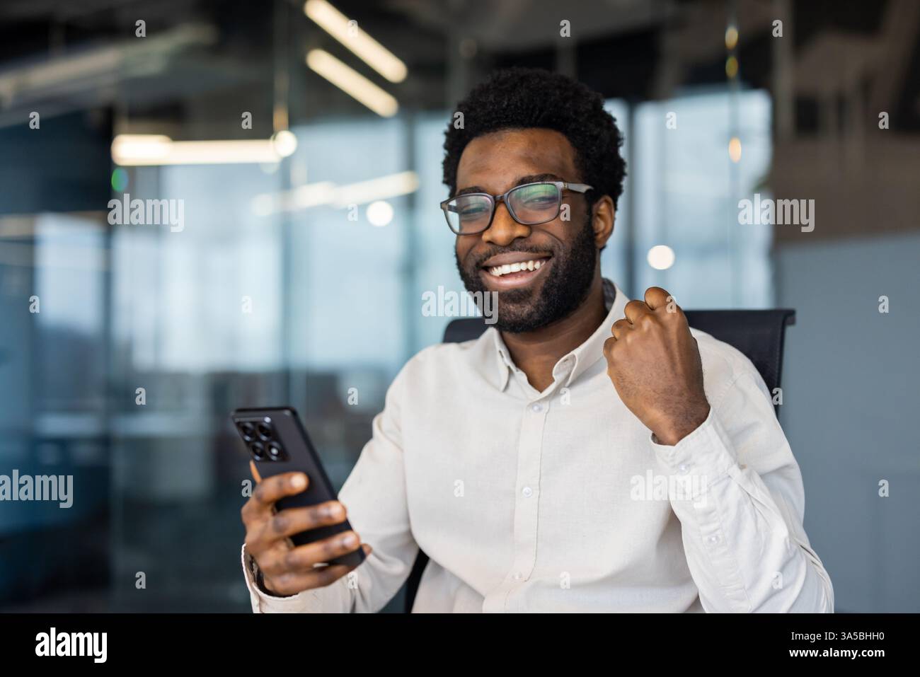 Enthusiastic businessman celebrates success while looking at his mobile ...