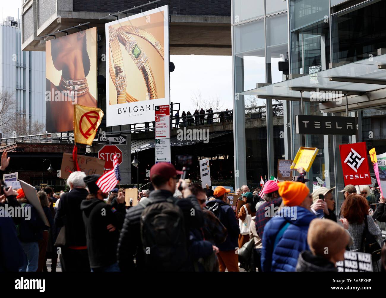 Protesters hold signs when they gather outside of the Tesla dealership ...