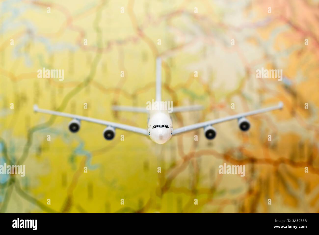 Detalle de un avión de pasajeros en miniatura volando sobre un mapa difuminado Stock Photo