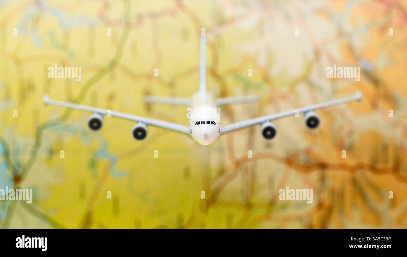 Detalle de un avión de pasajeros en miniatura volando sobre un mapa difuminado Stock Photo
