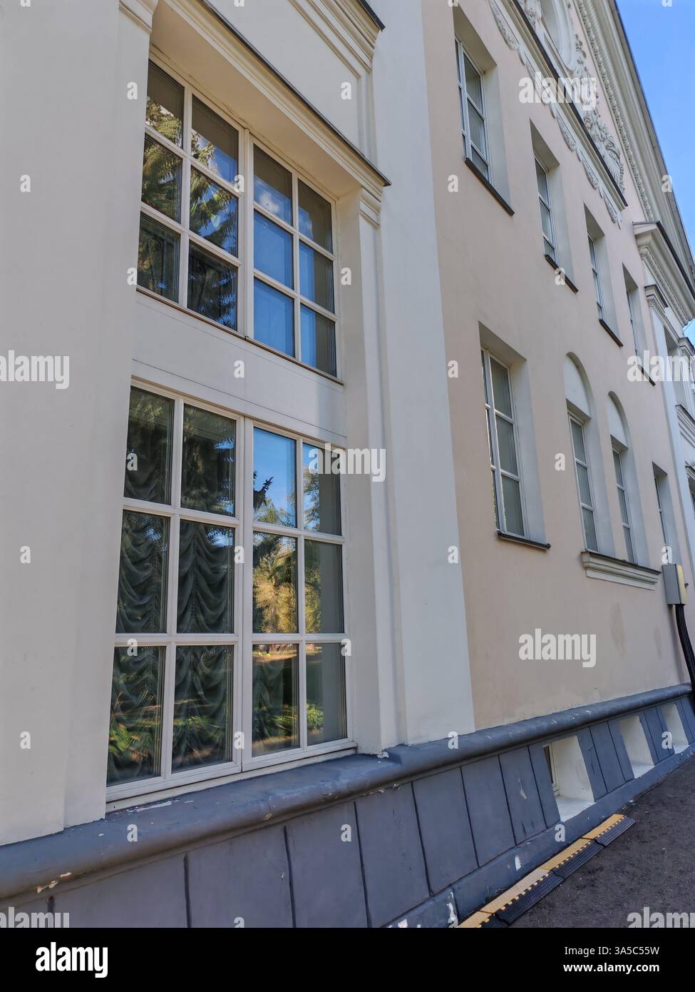 Large framed windows with tree reflections on a smooth beige facade ...