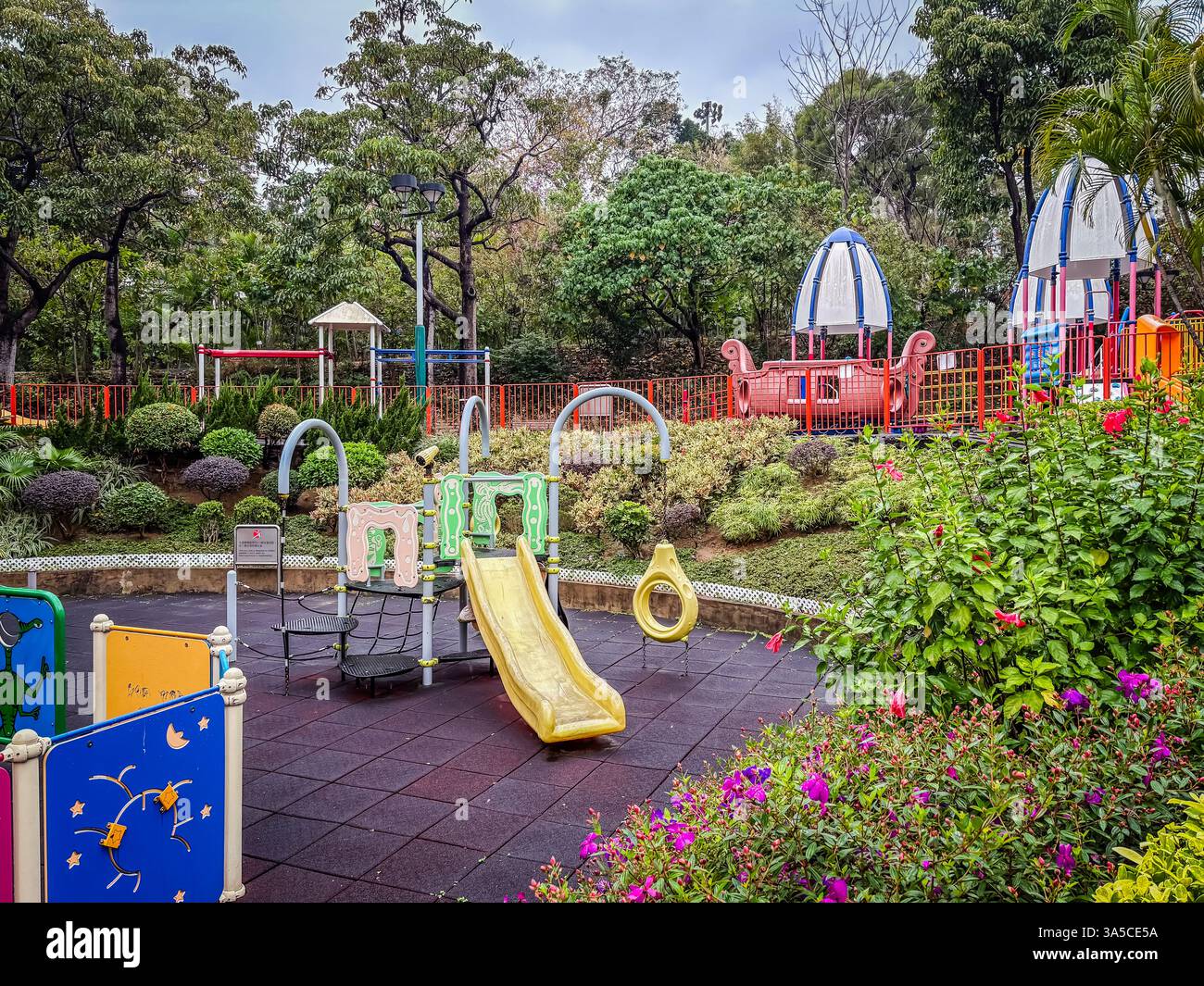 Playground at Kowloon Tsai Park in Hong Kong, featuring play equipment, greenery, and flowers. Stock Photo