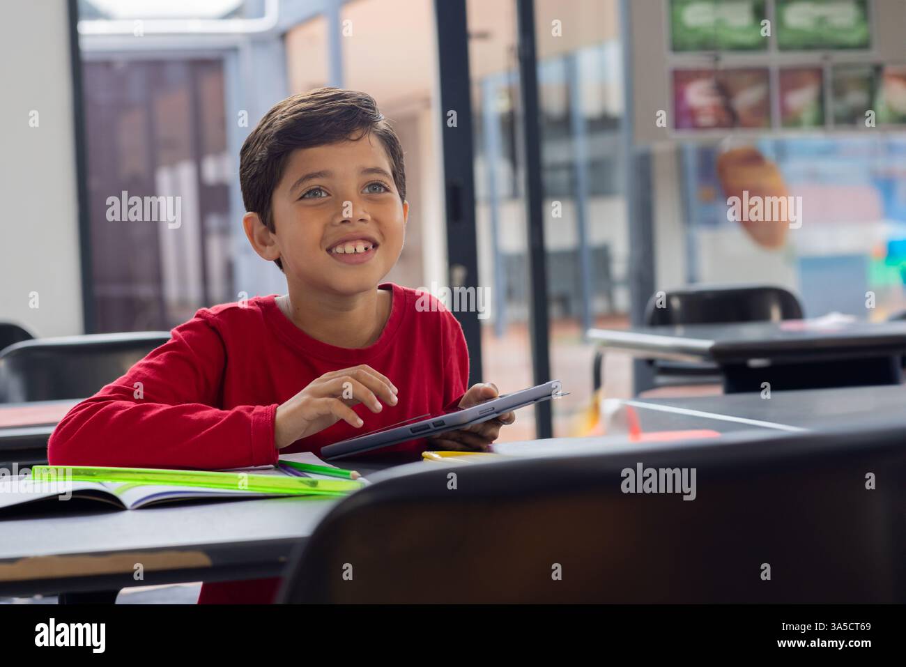 In school, smiling boy using tablet in classroom, engaging with technology, copy space Stock Photo