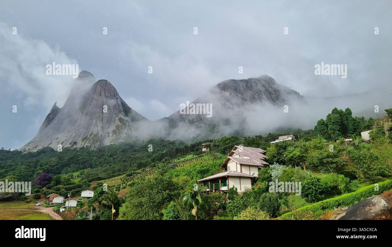 A serene rural valley stretches between lush green hills, where scattered houses rest quietly among trees and grassy fields. - Smartphone Captured Stock Image