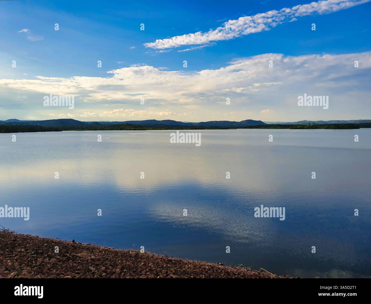 A serene lake reflecting the sky with clouds and sun rays, surrounded ...