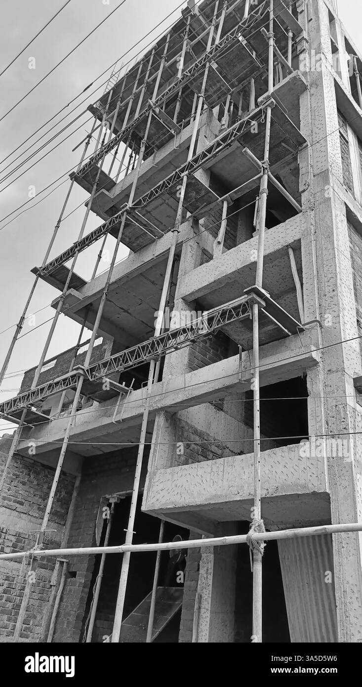 Workers are actively engaged in the construction of a multi-story building, with scaffolding in place for support and safety. Stock Photo