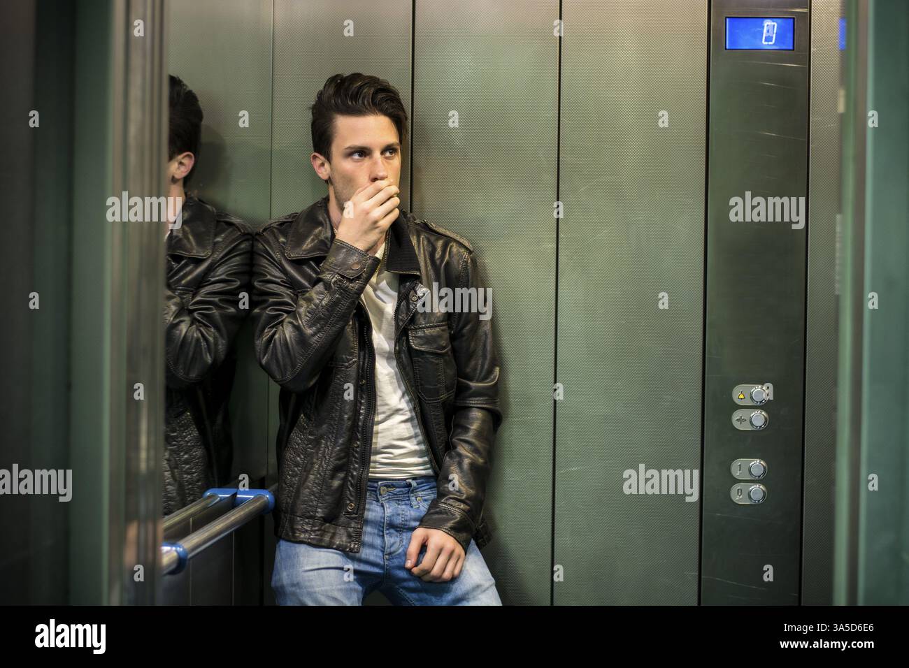 Scared young man desperate in stuck elevator screaming, looking very upset Stock Photo