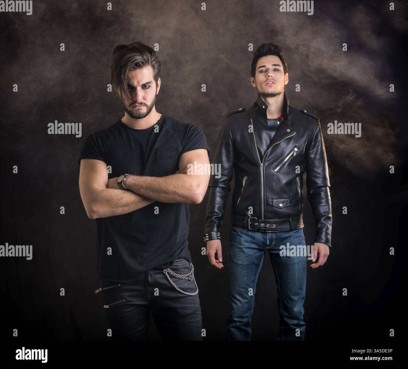 Two attractive young hard rock men posing in studio. Black background Stock Photo
