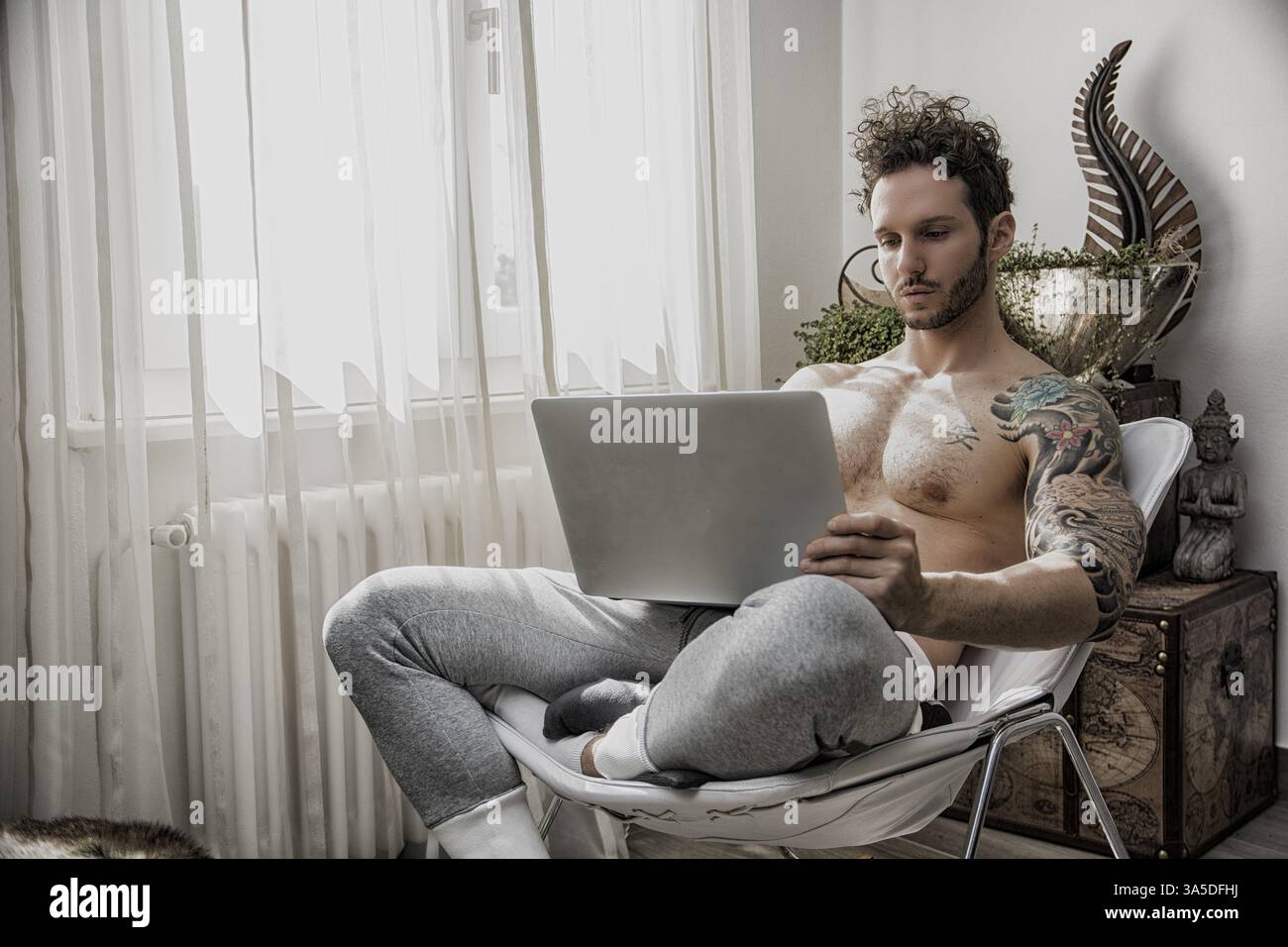 Waist Up Profile of Attractive Man with Muscular Body, Sitting with Computer Working or on His Start-up Business Stock Photo